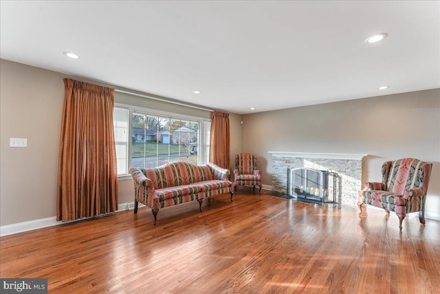 living area featuring a stone fireplace and wood-type flooring