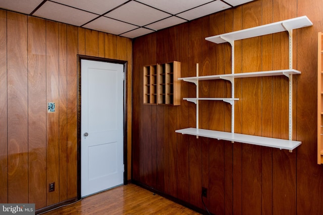 interior space featuring wood walls, a paneled ceiling, and wood-type flooring