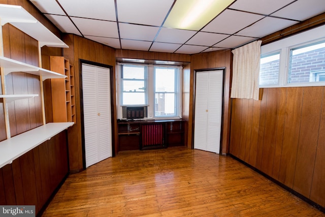 interior space featuring hardwood / wood-style floors, wood walls, and a paneled ceiling