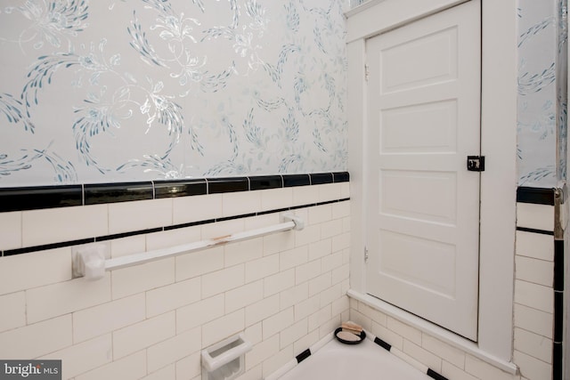 bathroom with a washtub and tile walls