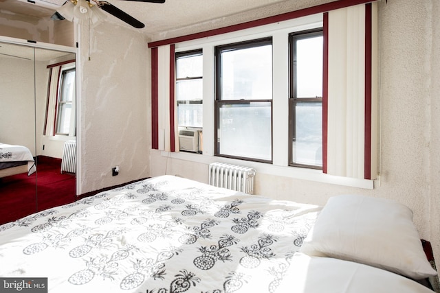 bedroom with a closet, cooling unit, ceiling fan, and radiator