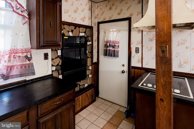 kitchen with dark brown cabinets, black oven, and light tile patterned floors