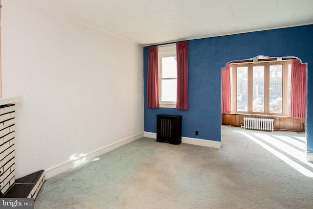 unfurnished room with radiator and light carpet