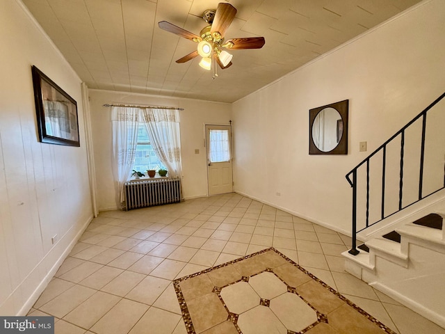 tiled foyer entrance with radiator, ceiling fan, and crown molding