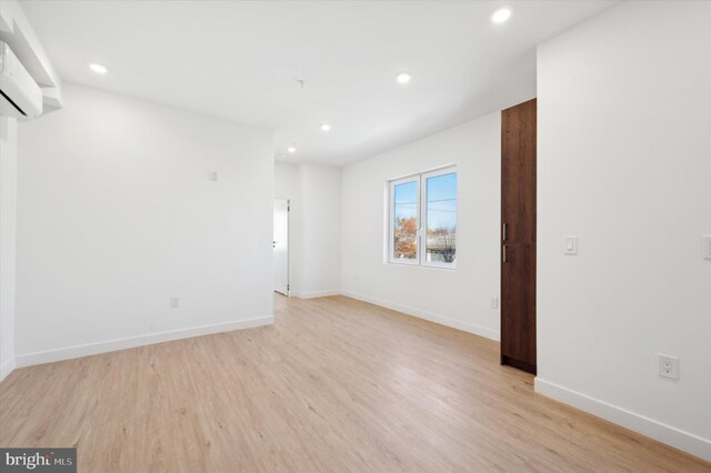 spare room with light wood-type flooring and a wall mounted air conditioner