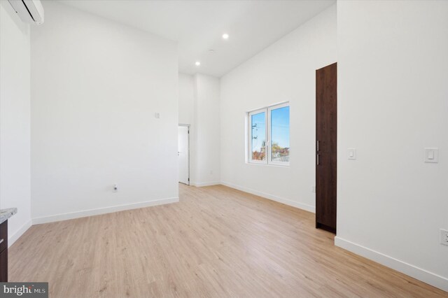 spare room featuring light hardwood / wood-style flooring and a wall mounted air conditioner