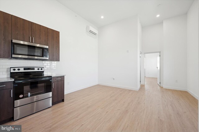 kitchen with backsplash, appliances with stainless steel finishes, dark brown cabinetry, and light hardwood / wood-style floors