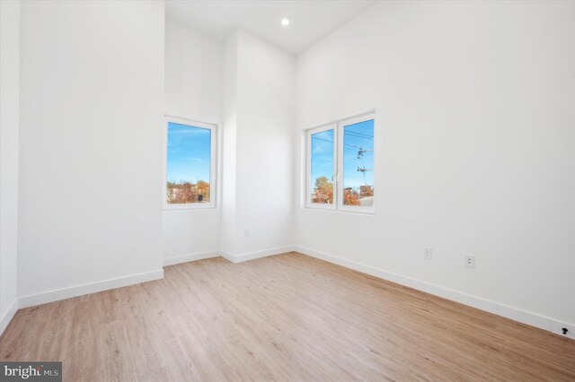 empty room featuring light hardwood / wood-style floors and a towering ceiling
