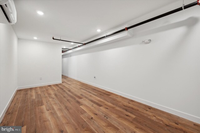 basement with light hardwood / wood-style floors and a wall mounted air conditioner
