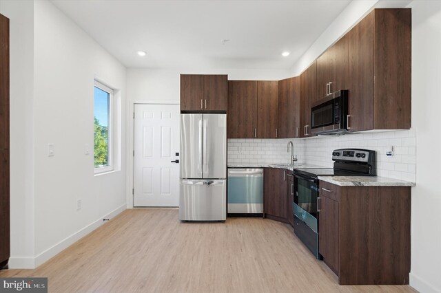 kitchen featuring black appliances, light stone counters, dark brown cabinetry, decorative backsplash, and light hardwood / wood-style floors