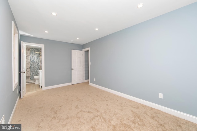 unfurnished bedroom featuring ensuite bath and light carpet