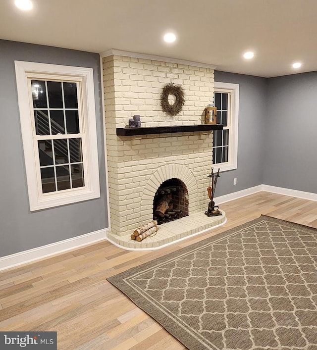 unfurnished living room with hardwood / wood-style floors and a brick fireplace