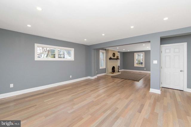 unfurnished living room featuring light wood-type flooring and a brick fireplace