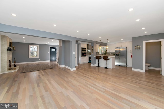 unfurnished living room with light wood-type flooring and a brick fireplace