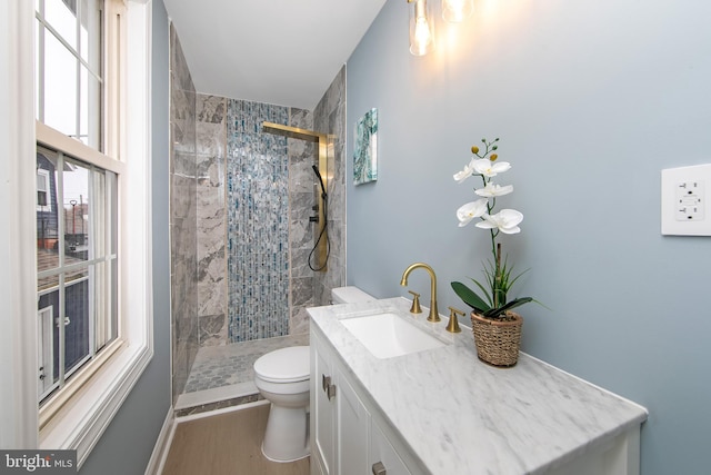 bathroom featuring tiled shower, hardwood / wood-style floors, vanity, and toilet