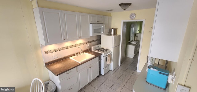 kitchen featuring white appliances, backsplash, white cabinets, sink, and light tile patterned floors