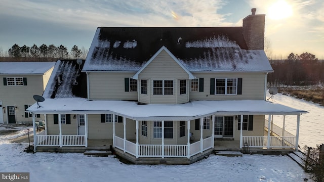 snow covered rear of property featuring covered porch