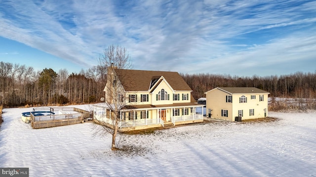 snow covered property featuring central AC and covered porch