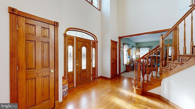 foyer entrance with light hardwood / wood-style floors and a high ceiling