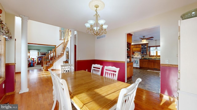 dining room with sink, ceiling fan with notable chandelier, dark wood-type flooring, and ornate columns