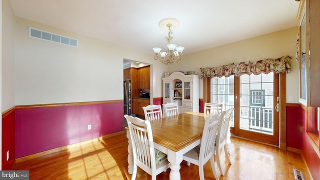 dining room with light hardwood / wood-style floors and a notable chandelier