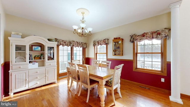 dining room with light hardwood / wood-style floors, a healthy amount of sunlight, and ornate columns