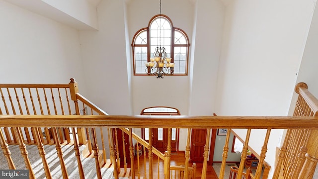 stairs with plenty of natural light, a towering ceiling, and a chandelier