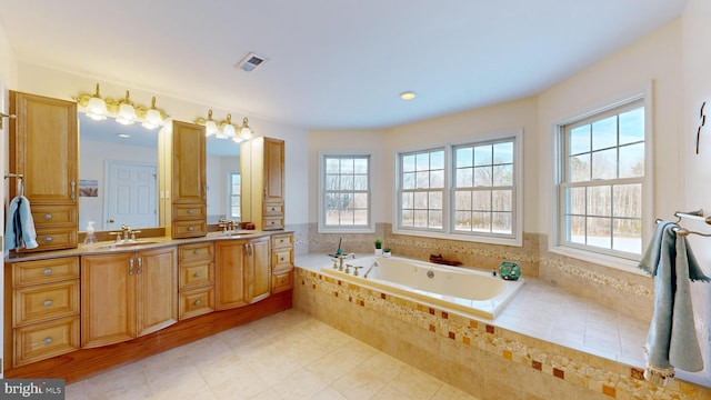 bathroom featuring tile patterned flooring, vanity, and tiled bath