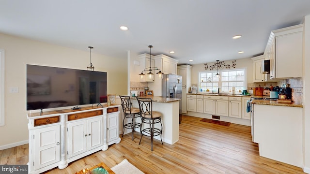 kitchen featuring a kitchen bar, sink, hanging light fixtures, appliances with stainless steel finishes, and backsplash