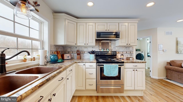 kitchen with appliances with stainless steel finishes, sink, white cabinets, decorative backsplash, and light stone countertops