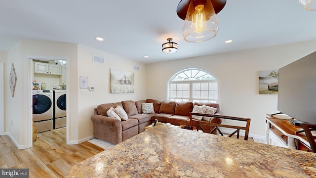 living room with light hardwood / wood-style floors and independent washer and dryer