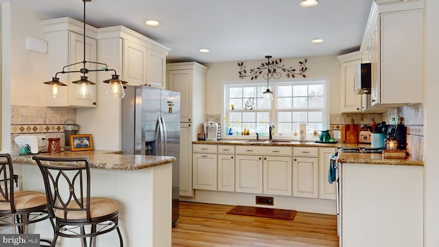 kitchen featuring hanging light fixtures, sink, backsplash, and stone counters