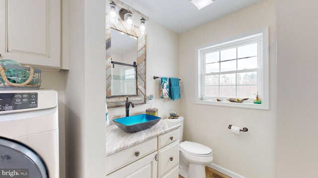 bathroom featuring vanity, toilet, and washer / dryer