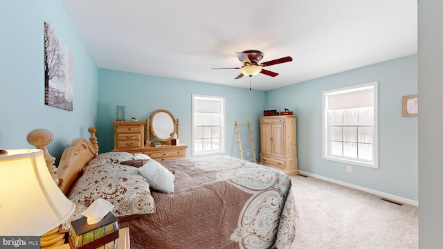 carpeted bedroom featuring multiple windows and ceiling fan