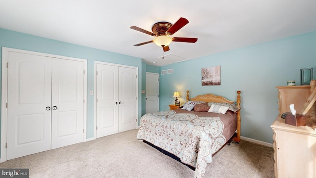 carpeted bedroom featuring multiple closets and ceiling fan