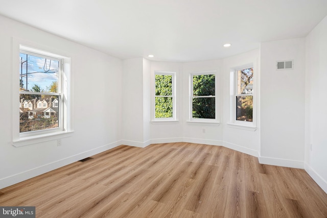 unfurnished room with a healthy amount of sunlight and light hardwood / wood-style floors