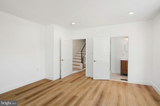 unfurnished bedroom with light wood-type flooring and connected bathroom