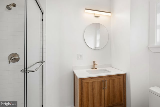 bathroom with vanity, toilet, and tiled shower