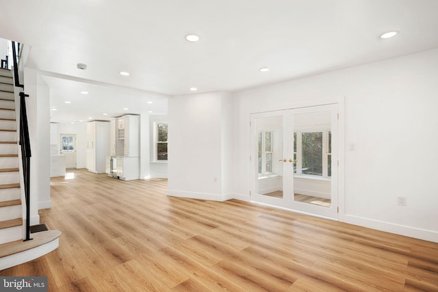 unfurnished living room featuring french doors and light hardwood / wood-style flooring