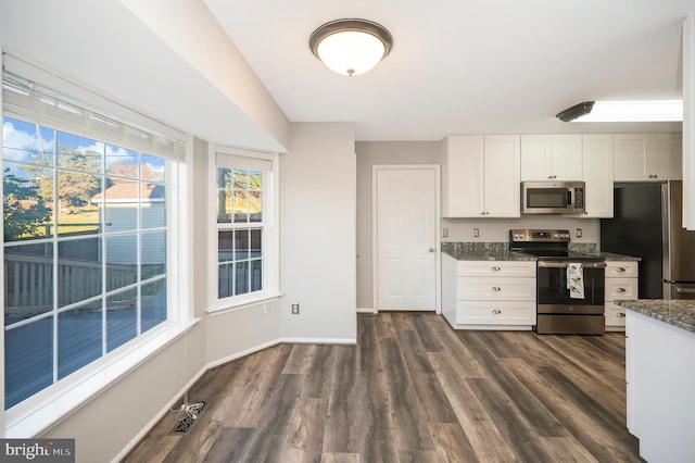 kitchen featuring dark stone counters, white cabinetry, dark wood-type flooring, and appliances with stainless steel finishes