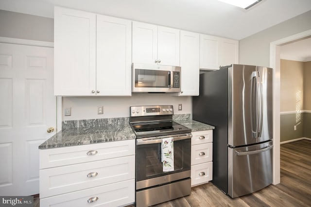 kitchen featuring dark hardwood / wood-style flooring, white cabinets, dark stone countertops, and stainless steel appliances