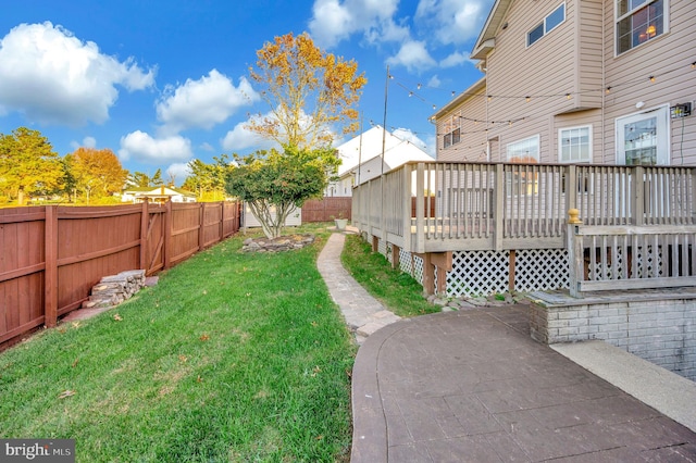 view of yard featuring a wooden deck and a patio