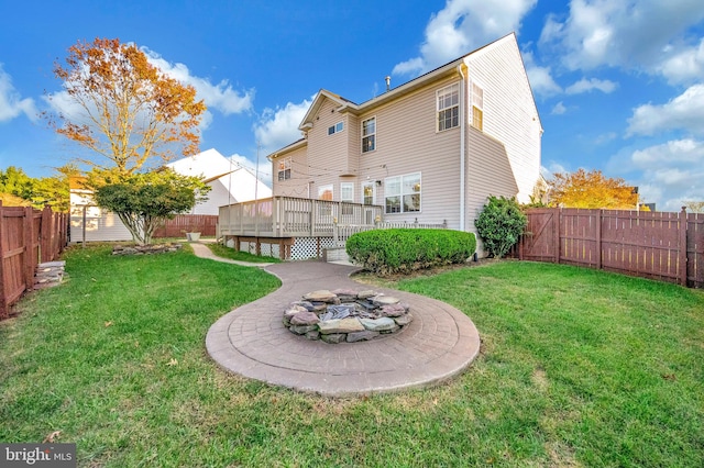 back of house with a lawn, an outdoor fire pit, and a wooden deck