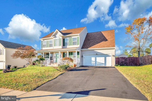 view of front of home featuring a garage, a front yard, and covered porch