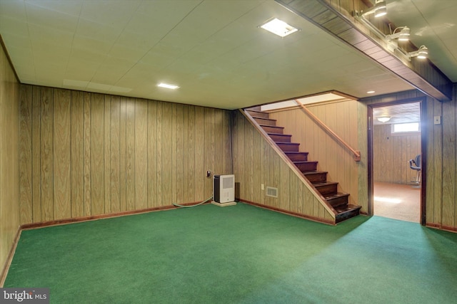 basement with wooden walls, carpet flooring, and heating unit