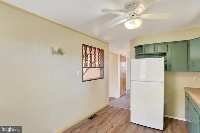 kitchen featuring ceiling fan, light hardwood / wood-style floors, white fridge, and green cabinetry