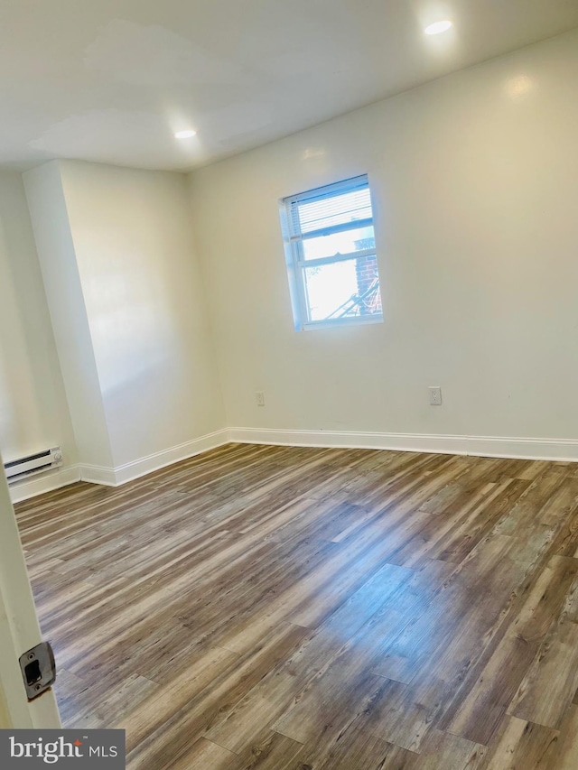 empty room featuring hardwood / wood-style floors and a baseboard radiator