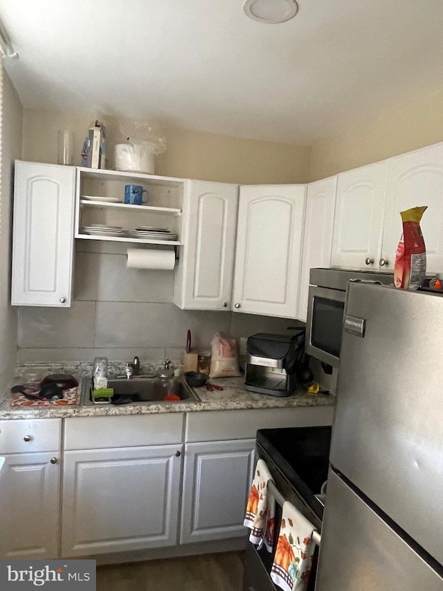 1525 W Wyoming Ave, Philadelphia, PA 19140 - kitchen featuring freestanding refrigerator, electric range, white cabinetry, and a sink