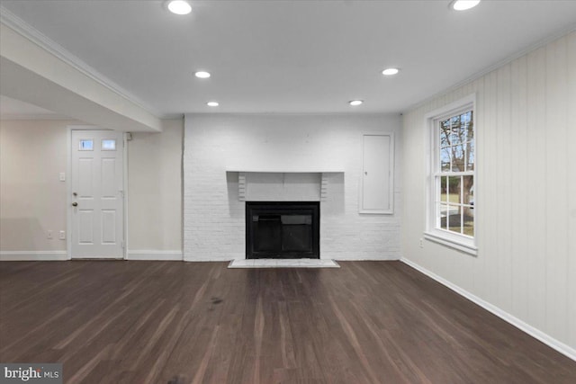 unfurnished living room featuring crown molding, dark hardwood / wood-style flooring, and a brick fireplace