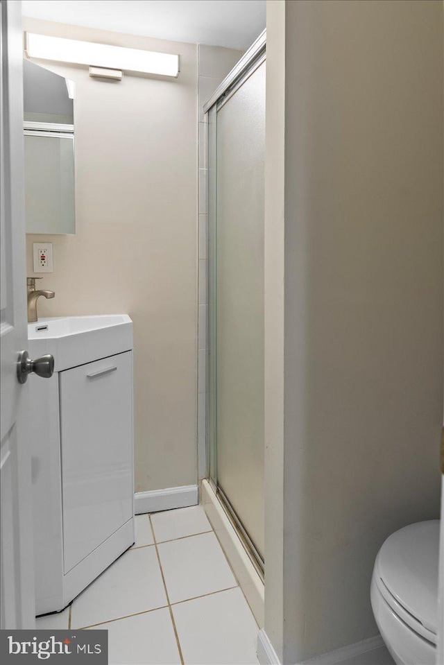 bathroom with toilet, vanity, a shower with door, and tile patterned flooring